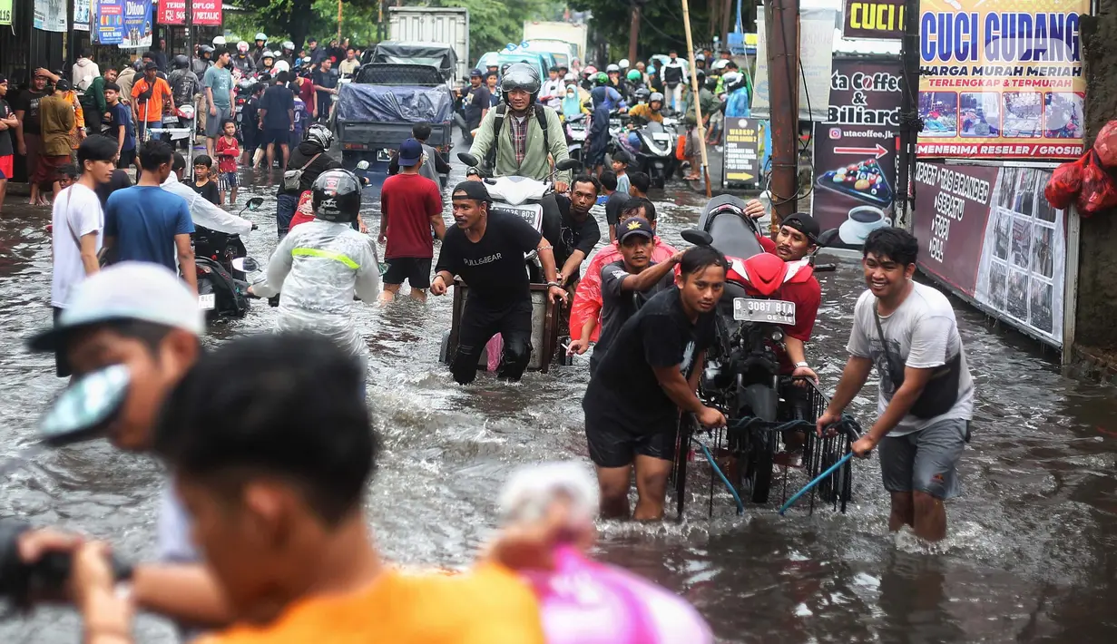 Sejumlah warga membawa motor di atas gerobak untuk melintasi banjir di kawasan Joglo, Jakarta, Jumat (22/3/2024). (Liputan6.com/Angga Yuniar)