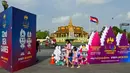 <p>Seorang wanita dan putrinya berjalan di samping tanda menjelang upacara pembukaan Pesta Olahraga Asia Tenggara (SEA Games) ke-32 di Phnom Penh, Kamboja, Kamis (4/5/2023). (TANG CHHIN Sothy/AFP)</p>