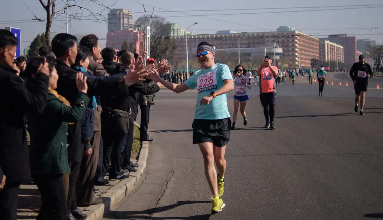 Pelari asing menyapa penonton selama Pyongyang Marathon atau yang disebut juga Mangyongdae Prize International Marathon di Pyongyang, Minggu (7/4). Ajang lari tahunan ini merupakan bagian dari perayaan untuk menandai hari lahir pendiri Korea Utara, Kim Il-sung pada tahun 1912. (KIM Won Jin / AFP)