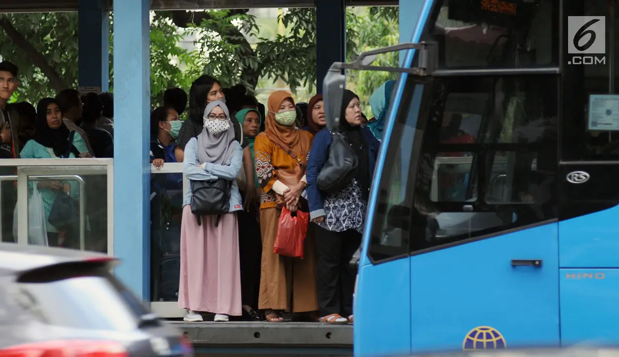 Warga menunggu bus Transjakarta di halte Bundaran Senayan, Jakarta, Jumat (14/7). Menurut Kepala Dinas LHK DKI Jakarta Isnawa Adji, kualitas udara yang buruk terjadi di hampir seluruh Jakarta terutama di pusat industri. (Liputan6.com/Helmi Fithriansyah)