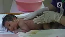 Perawat saat mempraktekan cara memandikan bayi kepada seorang ibu di RSIA Tambak, Jakarta, Kamis (18/02/2021). Melatih para ibu baru untuk memandikan bayi pertama tersebut dilakukan dengan menerapkan protokol kesehatan ketat. (Liputan6.com/Herman Zakharia)