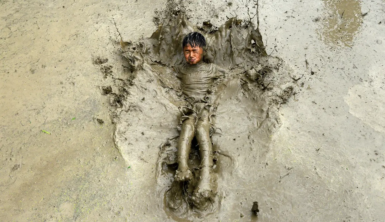 Seorang anak bermain lumpur pada Hari Padi Nasional di sawah Desa Tokha, Kathmandu, Nepal, Senin (29/6/2020). Para petani di Nepal merayakan Hari Padi Nasional sebagai musim tanam padi tahunan dimulai. (PRAKASH MATHEMA/AFP)