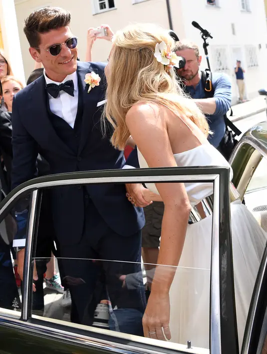 Penyerang Fiorentina, Mario Gomez menggandeng calon istrinya, Carina Wanzung usai keluar dari mobil untuk menggelar prosesi pernikahan di Munich, Jerman, (22/7). Carina Wanzung merupakan model pakaian renang. (AFP PHOTO/ Sven Hoppe)