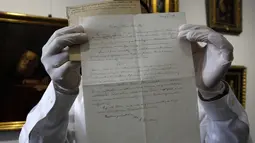 Petugas rumah lelang Winner menunjukkan surat rumusan "Tahap Ketiga Teori Relativitas" yang ditulis oleh Albert Einstein di Yerusalem, Selasa (6/3). Surat resmi tulisan tangan itu dikirim dari Berlin pada 1928 untuk ahli matematika. (MENAHEM KAHANA/AFP)