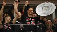 Pelatih Bayer Leverkusen, Xabi Alonso, berselebrasi dengan tiruan trofi Bundesliga setelah mengunci gelar berkat kemenangan atas Wender Bremen di  Leverkusen, Minggu (14/4/2024). (AFP/Ina Fassbender)