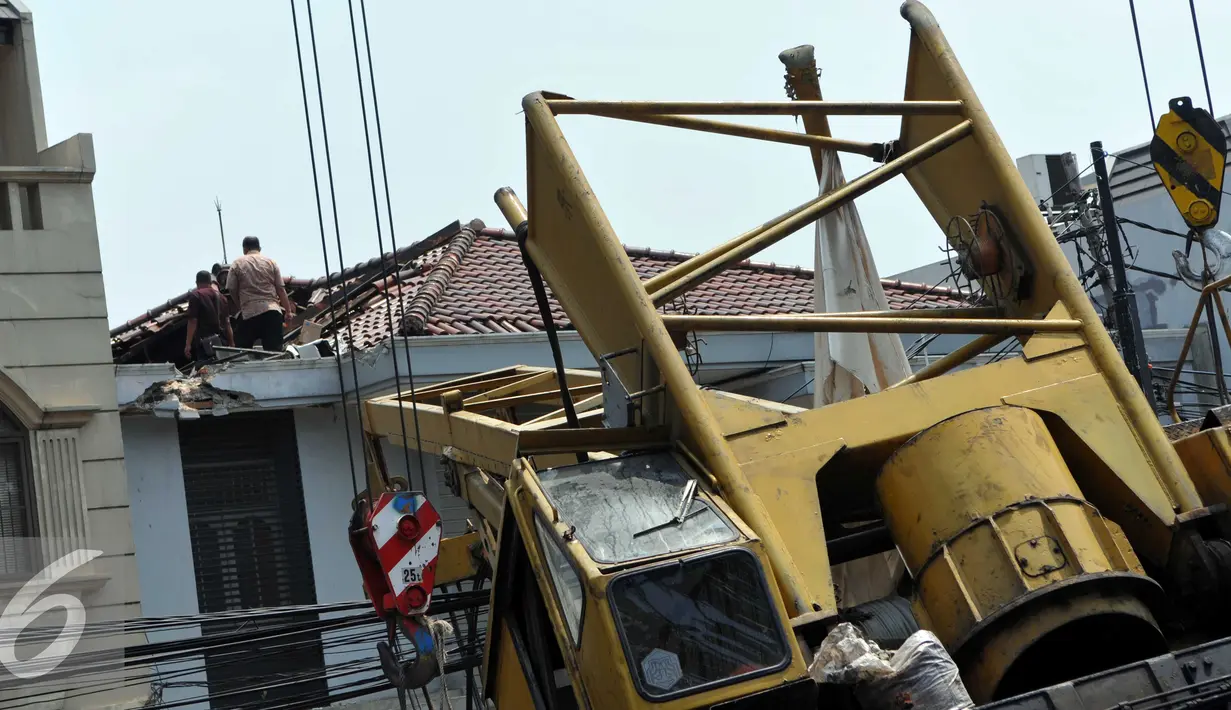 Pekerja mengevakuasi crane yang jatuh di Jalan Kyai Maja, Jakarta Selatan, Kamis (15/10/2015). Alat besar yang tengah melakukan proyek ‎jalan layang ini menimpa salah satu rumah warga yang berada di sisi kanan jalan. (Liputan6.com/Helmi Afandi)