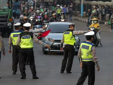 Petugas polisi lalu lintas memberi arahan kepada pengguna mobil saat pemberlakuan sistem ganjil genap di pintu masuk Gardu Tol Cibubur 2, Jakarta, Senin (16/4). (Liputan6.com/Faizal Fanani)