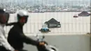 Pengendara melintas saat kapal tunda terlihat menarik tongkang bermuatan batu bara di Sungai Mahakam di Samarinda, Kalimantan Timur, Indonesia, pada 19 Agustus 2026. (AP Photo/Ahmad Mulia Panjaitan)