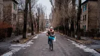 Seorang wanita mengendarai sepeda di sebuah jalan kosong di Chasiv Yar, dekat Bakhmut pada 28 Februari 2023. Pihak berwenang Ukraina mengatakan pada 28 Februari, pasukannya berada di bawah tekanan di Bakhmut, sebuah kota yang hampir hancur di wilayah Donetsk timur yang telah berusaha direbut Rusia selama berbulan-bulan. (Dimitar DILKOFF/AFP)
