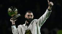 Pemain Real Madrid Karim Benzema berpose di lapangan dengan trofi Ballon d'Or miliknya pada babak pertama pertandingan sepak bola L1 Prancis antara Olympique Lyonnais (OL) dan OGC Nice di Stadion Groupama, Decines-Charpieu, Prancis, 11 November 2022. Karim Benzema memamerkan trofi Ballon d'Or kepada para fans Olympique Lyon yang notabenenya adalah kota kelahirannya. (OLIVIER CHASSIGNOLE/AFP)