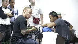 Pelatih Craig Christian sedang memasang perban pada tangan Daud Yordan diruang ganti sebelum bertanding melawan Yoshitaka Kato di Balai Sarbini, Jakarta, Jumat (5/2/2016). (Bola.com/Nicklas Hanoatubun)