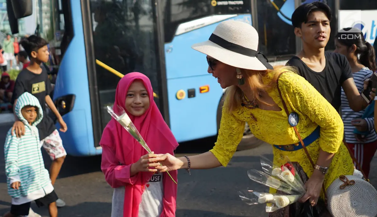 Sejumlah relawan membagikan bunga mawar ke warga saat berlangsungnya kegiatan car free day di kawasan Bundaran HI, Jakarta, Minggu (30/6/2019).  Aksi 1000 bunga mawar itu sebagai bentuk rasa syukur atas kemenangan pasangan Jokowi-Ma'ruf Amin di Pilpres 2019. (Liputan6.com/Immanuel Antonius)