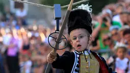 Seorang anak berlari sambil memasukan tombak kayu ke lubang sasaran selama turnamen tradisional Alka di desa Vuckovici, Kroasia, Minggu (23/8/2015).  Alka adalah turnamen yang diselenggarakan setiap bulan Agustus sejak 1955. (REUTERS/Antonio Bronic)