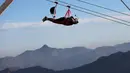 Wisatawan meluncur dengan flying fox dari atas Gunung Jabel Jais Ras al-Khamiah di Uni Emirat Arab, 31 Januari 2018. Flying fox yang diklaim terpanjang di dunia tersebut dirancang untuk mampu melayani 250 orang per harinya. (AP/Kamran Jebreili)