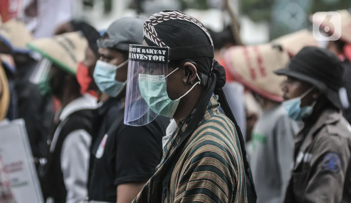 Buruh tani mengenakan faceshield saat ikut dalam aksi menolak UU Omnibus Law Cipta Kerja di Jalan Salemba Raya, Jakarta, Selasa (20/10/2020). Ratusan buruh dan tani dari berbagai daerah tersebut akan menggelar aksi di Istana Negara menolak UU Omnibus Law Cipta Kerja. (merdeka.com/Iqbal S. Nugroho)