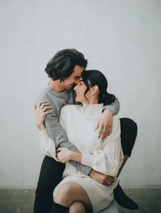 Dengan latar dinding putih polos, Tyas dan Tengku tampak serasi mengenakan sweater. [@@morden.co]