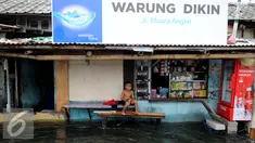 Seorang anak duduk di depan rumahnya yang tergenang air di Kawasan Muara Angke, Jakarta, Rabu (11/1). Banjir yang terjadi hampir setiap hari dalam satu bulan terakhir akibat rob yang diperparah dengan jebolnya tanggul. (Liputan6.com/Gempur M. Surya)