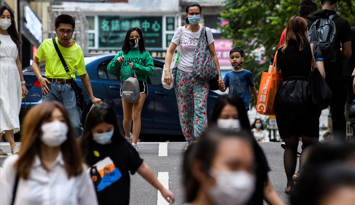 Pejalan kaki mengenakan masker sebagai tindakan pencegahan Covid-19 saat berjalan di Hong Kong (13/5/2020). Dua orang di Hong Kong dinyatakan positif Covid-19, mengakhiri perjalanan 24 hari tanpa kasus baru yang mulai melonggarkan peraturan jarak sosial. (AFP/Anthony Wallace)