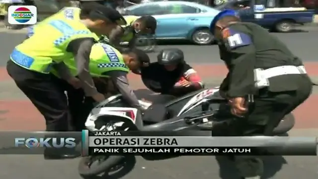 Petugas menolong ibu-ibu pengendara sepeda motor yang jatuh saat Operasi Zebra di Jalan Jatinegara Timur, Jakarta Timur.