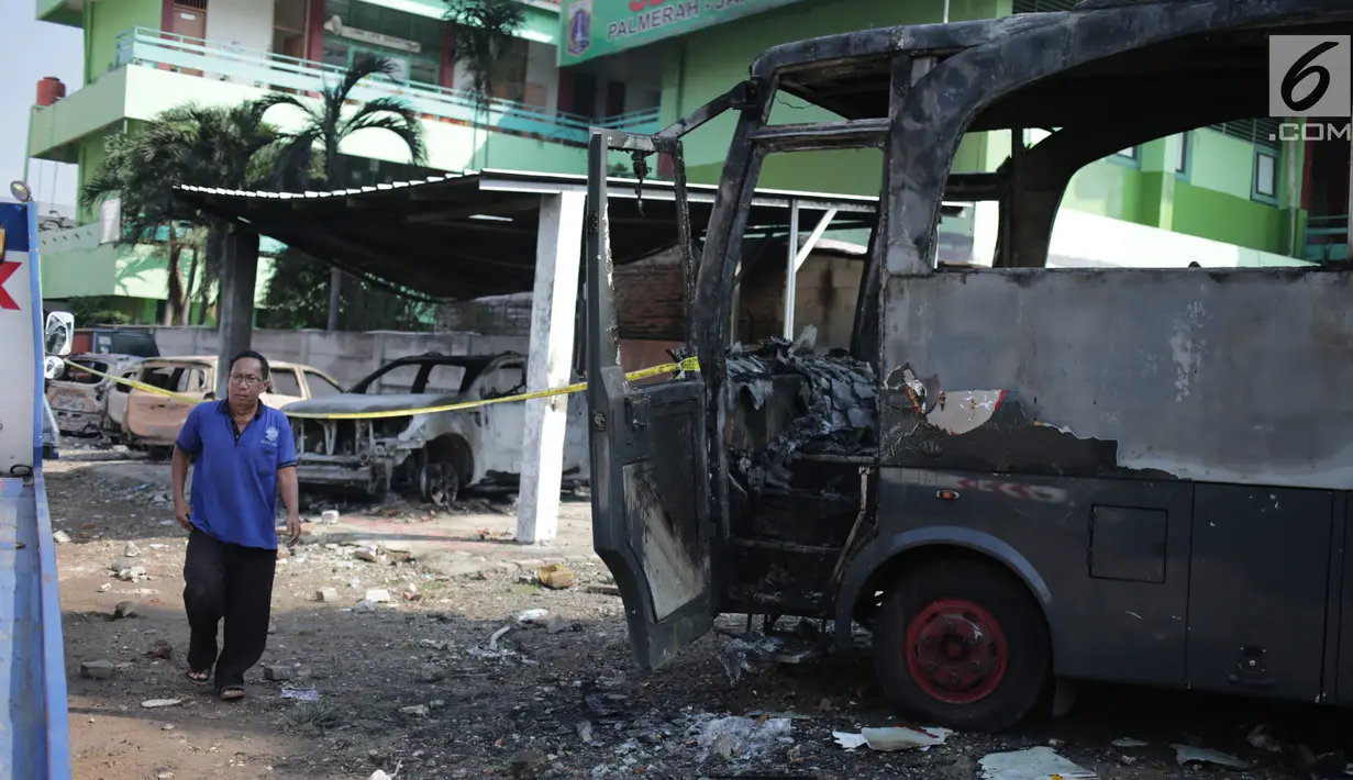 Seorang pria melintas dekat bangkai sebuah bus yang terbakar di sekitar asrama Brimob Jalan KS Tubun, Petamburan, Jakarta Barat, Rabu (22/5/2019). Diketahui kerusuhan terjadi di lokasi tersebut, buntut demo depan gedung Bawaslu yang berujung ricuh. (Liputan6.com/Faizal Fanani)
