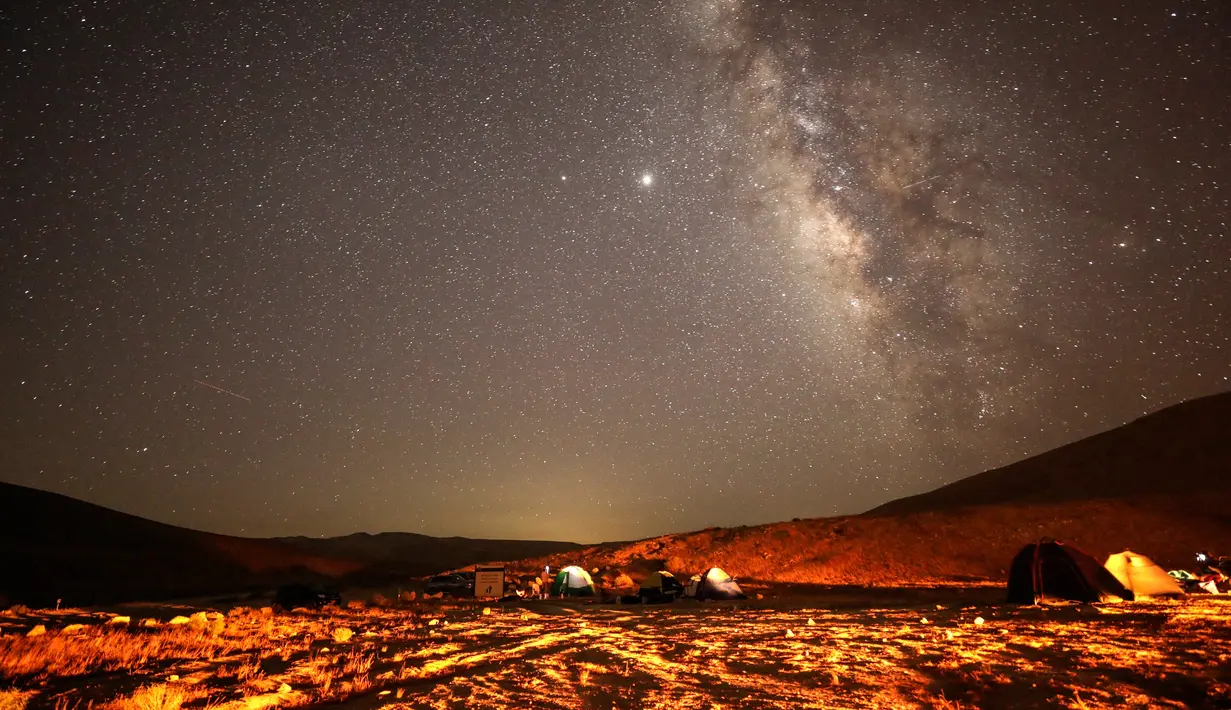 Meteor Perseid melintas di langit di atas lokasi perkemahan di gurun Negev dekat kota Mitzpe Ramon, Israel pada 11 Agustus 2020. Hujan meteor ini terjadi setiap tahun sekitar bulan Agustus, saat Bumi melayang melalui awan yang ditinggalkan oleh komet raksasa 109P / Swift-Tuttle. (MENAHEM KAHANA/AFP)