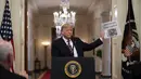 Presiden Donald Trump mengangkat sebuah surat kabar di hadapan awak media Ruang Timur Gedung Putih, Washington (6/2/2020). Surat kabar bertajuk utama tersebut bertuliskan "Trump dibebaskan". (AP Photo/Evan Vucci)