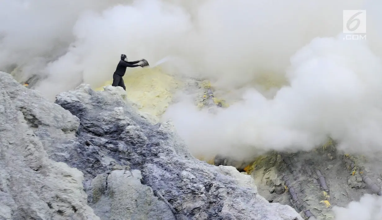 Penambag menyiram api biru dengan air karena api biru membakar blerang di Kawah Ijen, Banyuwangi, Jawa Timur, Senin (2/7). Para penambang mulai mengangkut belerang pada pukul 01.00 dinihari dengan jarak jarak 10 km bolak balik. (Merdeka.com/Arie Basuki)