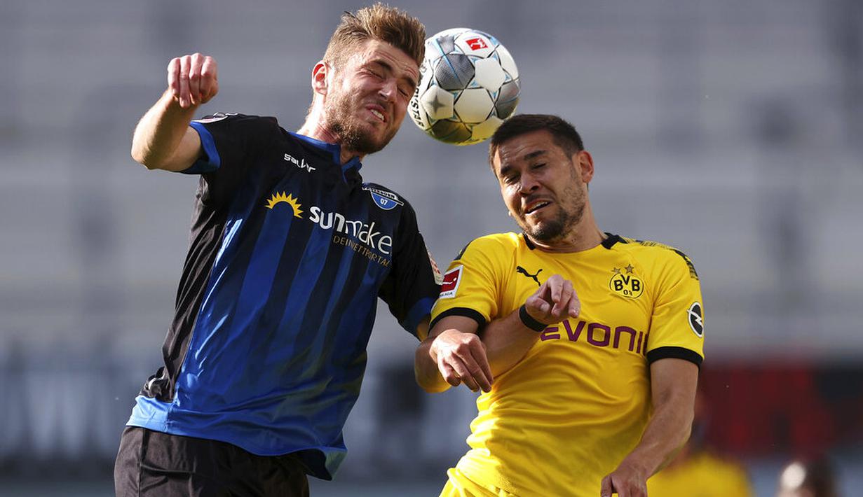 Pemain Borussia Dortmund, Raphael Guerreiro, berebut bola dengan pemain SC Paderborn 07, Dennis Srbeny, pada laga Bundesliga di Stadion Benteler, Minggu (31/5/2020). Borussia Dortmund menang dengan skor 6-1 SC Paderborn 07. (AP/Lars Baron)