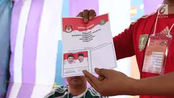 Petugas KPPS menunjukkan surat suara pada Pilkada Serentak 2018 di TPS 29 Gandasari, Kota Tangerang, Rabu (27/6). Di TPS ini warga yang menggunakan hak pilih untuk Pilkada Kota Tangerang dapat merasakan sensasi Piala Dunia 2018 (Liputan6.com/Angga Yuniar)