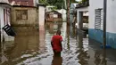 Seorang pria berjalan di sepanjang jalan yang terendam banjir setelah badai tropis Melissa berlalu sebelum berubah menjadi badai di kawasan Las Cucarachas di Santo Domingo, Republik Dominika pada Selasa 28 Oktober 2025. (Danny Polanco/AFP)