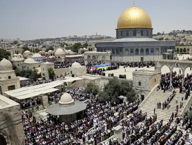 Jemaah muslim Palestina melaksakan salat di depan Dome of the Rock atau Kubah Shakhrah yang berada di tengah kompleks Masjid Al Aqsa, Yerusalem (8/6). (AP/Mahmoud Illean)