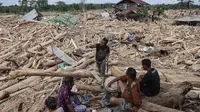 Dalam catatan Badan Nasional Penanggulangan Bencana (BNPB), bencana banjir dan longsor di Aceh Tamiang mengakibatkan kerusakan sebanyak 2.800 unit rumah, 127 fasilitas umum, 62 gedung atau kantor, 54 fasilitas pendidikan, 40 fasilitas kesehatan, 33 rumah ibadah, dan dua jembatan. Tampak dalam foto, warga beristirahat sambil mencari sisa-sisa rumah mereka yang terkubur di bawah tumpukan pohon tumbang yang disapu banjir bandang, di desa Lintang Baru di Aceh Tamiang, Sumatera Utara, pada Kamis 11 Desember 2025. (Aditya Aji/AFP)