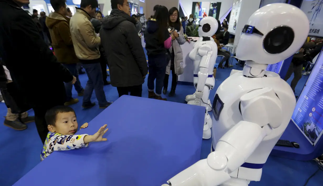 Seorang saat melihat Robot yang berbentuk mirip manusia yang bernama Robot KINGER pada Pameran Dunia Robot selama Konferensi Robot Dunia di Beijing, Cina,  (24/11). Konferensi robot ini diadakan selama tiga hari dari senin lalu. (REUTERS/Jason Lee)