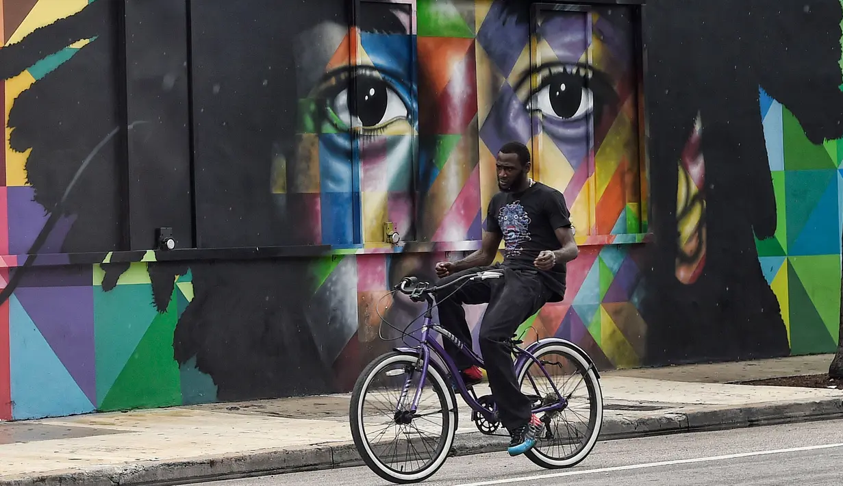Seorang pria bersepeda melintas di depan mural karya seniman Brasil Kobra di kawasan Wynwood, Miami, Florida pada 28 September 2016. Goldman Properties menggelar pameran mural untuk merevitalisasi lingkungan. (AFP PHOTO / Rhona WISE)