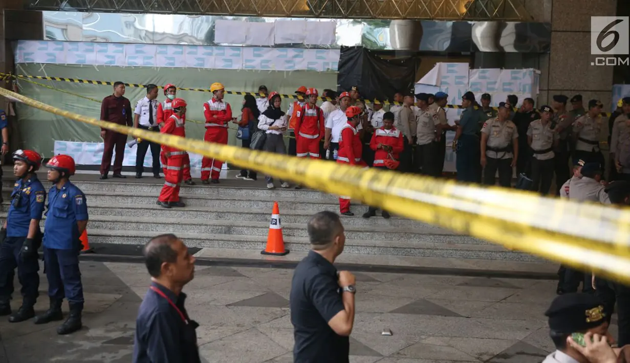Sejumlah petugas bersiaga dekat garis polisi yang terpasang setelah ambruknya Selasar Tower II Gedung Bursa Efek Indonesia (BEI), Jakarta, Senin (15/1). Pelataran gedung BEI masih dipenuhi petugas yang melakukan proses evakuasi. (Liputan6.com/Johan Tallo)