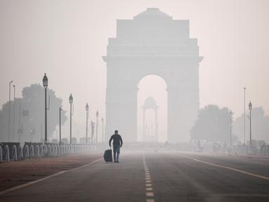 Seorang pria melintas di sepanjang jalan Rajpath dekat Gerbang India di tengah kondisi asap tebal yang menyelimuti sehari setelah perayaan Diwali, festival cahaya Hindu, di New Delhi pada Minggu (15/11/2020). (Photo by Sajjad HUSSAIN / AFP)