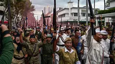Anggota Komunitas Roode Brug Soerabaia dan Reenactor Indonesia berpartisipasi dalam reka ulang Pertempuran Surabaya, pada Minggu 2 November 2025. Anggota komunitas sejarah Roode Brug Soerabaia dan Reenactor Indonesia menggelar reka ulang peristiwa Pertempuran Surabaya, di sekitar kawasan Tugu Pahlawan hingga Balai Pemuda, Kota Surabaya, Jawa Timur, Minggu 2 November 2025. (Juni KRISWANTO/AFP)