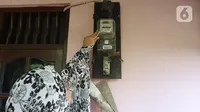 Warga memeriksa meteran listrik di kawasan Matraman, Jakarta, Kamis (2/4/2020). Di tengah pandemi COVID-19, pemerintah menggratiskan biaya tarif listrik bagi konsumen 450 Volt Ampere (VA) dan pemberian keringanan tagihan 50 persen kepada konsumen bersubsidi 900 VA. (Liputan6.com/Herman Zakharia)