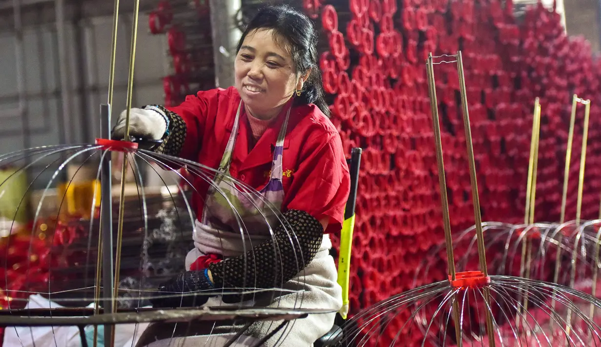 Seorang pekerja membuat lentera merah menjelang perayaan Tahun Baru Imlek 2020 di sebuah pabrik di Wuyi, China, Kamis (26/12/2019). Beberapa keunikan pada tradisi perayaan Imlek yang masih dijalani warga Tionghoa adalah menggantung lentera merah. (Photo by STR / AFP)