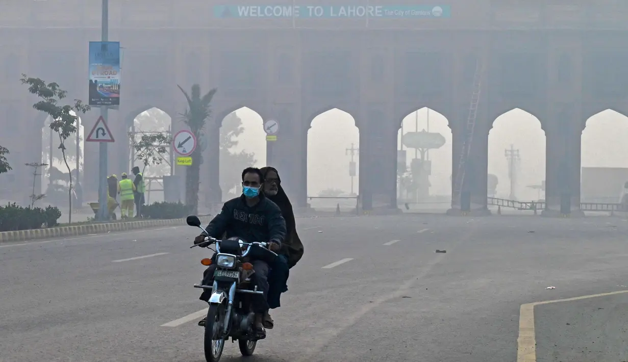Pengendara sepeda motor melintasi jalan di tengah kabut asap pekat di Lahore pada 24 November 2023. (Arif ALI/AFP)