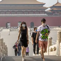 Para pengunjung mengenakan masker saat berjalan di Kota Terlarang, Beijing, China, Jumat (1/5/2020). Kota Terlarang kembali dibuka setelah ditutup lebih dari tiga bulan karena pandemi virus corona COVID-19. (AP Photo/Mark Schiefelbein)