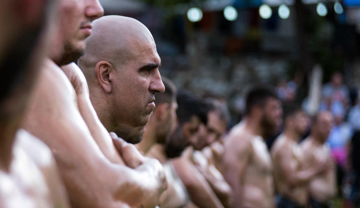 Para peserta gulat berbaris sebelum ambil bagian dalam kompetisi tahunan gulat minyak tradisional di Sochos, Yunani, 30 Juni 2018. Pertandingan perpaduan tradisi Yunani kuno dan zaman modern itu diiringi musik tradisional. (AP/Giannis Papanikos)