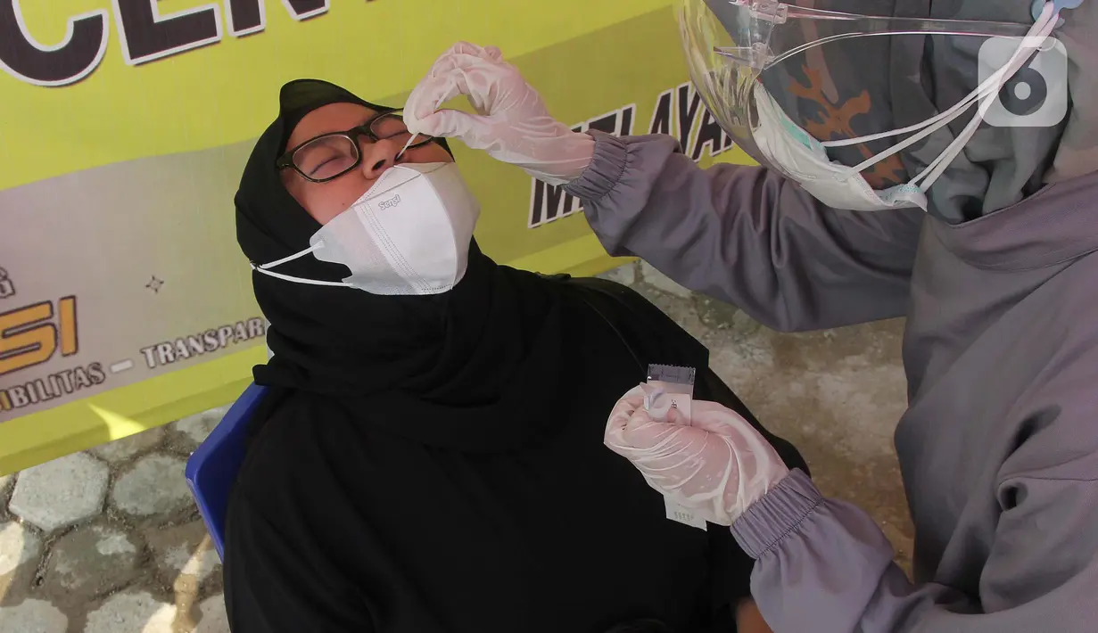 Petugas mengambil sampel lendir hidung untuk pemeriksaan tes swab antigen di Polsek Pamulang, Tangerang Selatan pada Rabu (19/5/2021). Swab antigen gratis itu bagi warga Pamulang yang sudah kembali usai menjalani perjalanan mudik untuk antisipasi penularan virus corona. (merdeka.com/Arie Basuki)