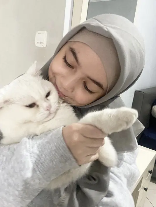 Sienna pun tampil menggemaskan dengan kucingnya, dalam potret tersebut, ia mengenakan kerudung abu-abu serasi dengan sweaternya.  Credit: (@nesyanabila)
