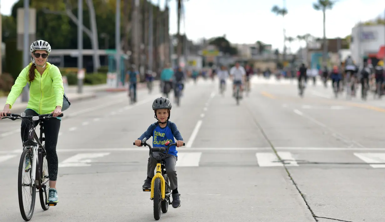 Seorang wanita dan anak kecil mengendarai sepeda di jalan-jalan bebas kendaraan bermotor selama acara CicLAvia di Culver City, Los Angeles, Minggu (3/3). Di Los Angeles, car free day disebut juga CicLAvia. (Chris Delmas/AFP)