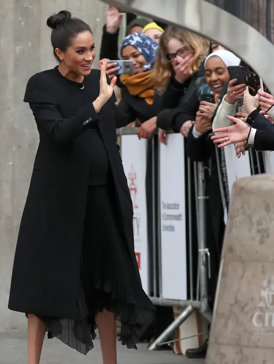 Duchess of Sussex, Meghan Markle seusai mengunjungi Association of Commonwealth Universities (ACU) di London, Kamis (31/1). Meghan tampil dalam balutan coat hitam rancangan Givenchy untuk membungkus dress dengan rok lipit. (Daniel LEAL-OLIVAS / AFP)