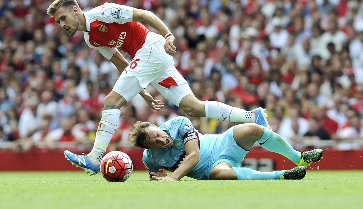 Pemain West Ham, Mark Noble (bawah), berusaha menghentikan langkah Aaron Ramsey dalam pertandingan di Stadion Emirates, London. Minggu (9/8/2015). (EPA/Gerry Penny)