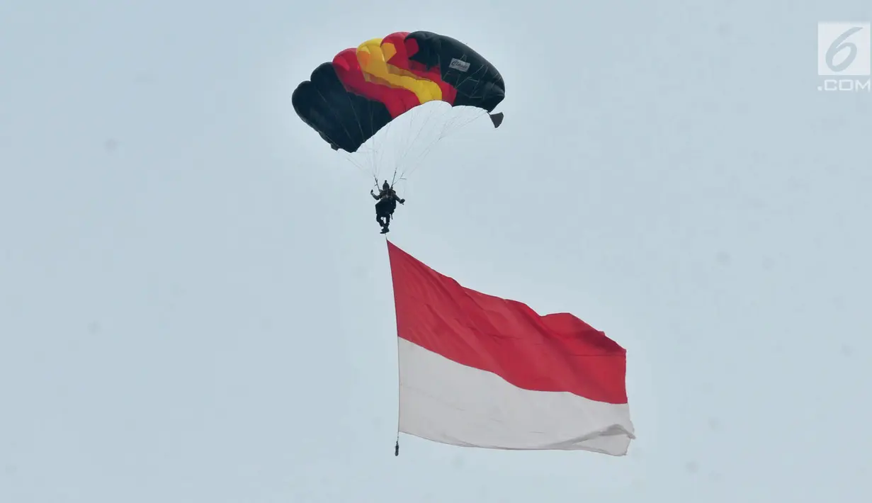 Penerjun payung membawa bendera Merah Putih saat Festival Damai Millenial Road Safety di Monas, Jakarta, Minggu (23/6/2019). Aksi puluhan penerjun payung TNI-Polri ini menjadi perhatian warga di akhir acara Festival Damai. (merdeka.com/Iqbal Nugroho)