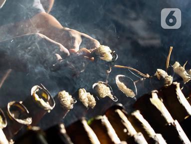 Pekerja melakukan pembakaran lemang bambu di Jalan Kramat Raya, Senen, Jakarta Pusat, Rabu (6/4/2022). Selama Ramadhan, pembuat lemang mampu memproduksi hingga 300 buah dalam sehari, meningkat hingga tiga kali lipat dari hari biasa. (Liputan6.com/Herman Zakharia)