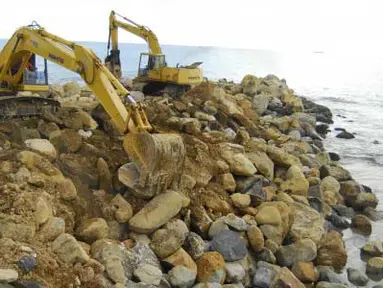 Dua alat berat mengangkat batu gunung untuk disusun datar menjorok kelaut (batu grip) di Pantai Padang, Sumbar, Selasa (10/4). Pembuatan batu grip (pemecah ombak) tersebut merupaka salah satu langkah untuk mengatasi ambrasi pantai Kota Padang yang setiap tahun luas dataran kota ini selalu berkurang akibat abrasi pantai. (Antara)